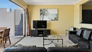 Una sala de estar moderna con un televisor de pantalla plana, un sofá, una mesa de centro y un cuadro en la pared.