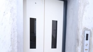 Puerta de ascensor blanca con marco negro y un panel de control en la pared.