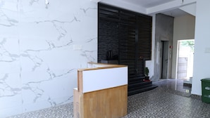 Una habitación con pared de mármol, un escritorio de madera, piso de baldosas y una puerta oscura.