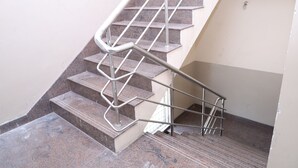 Una escalera con barandales de metal y peldaños de granito.