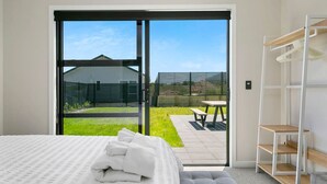 Une chambre moderne dotée d’une grande porte-fenêtre coulissante donnant sur un patio avec une table et des chaises.