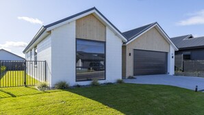 Une maison moderne à deux étages, dotée d’un garage, d’une pelouse bien entretenue et d’une allée d’accès fermée par un portail.