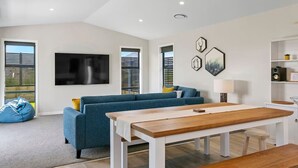 Un salon moderne avec un canapé bleu, une table à manger en bois et un téléviseur à écran plat fixé au mur.