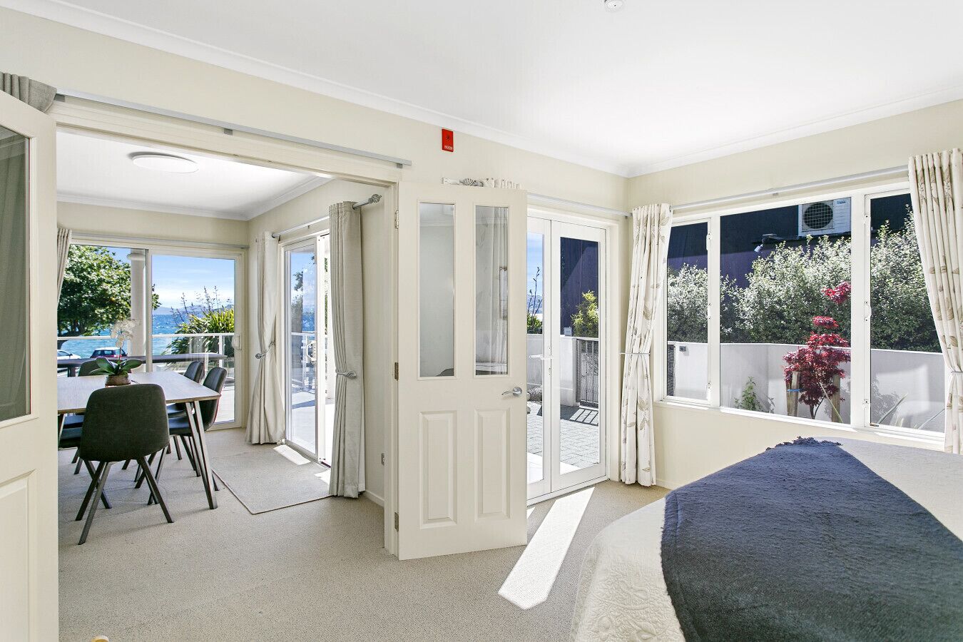 Une pièce comprenant un coin repas, une porte-fenêtre coulissante donnant sur un balcon et offrant une vue sur l’extérieur.