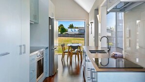 Een moderne keuken met een centraal eiland, een zithoek met stoelen en uitzicht op een achtertuin.