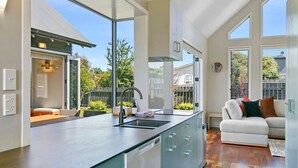 Een moderne keuken met een groot eiland, een eetgedeelte met een tafel en stoelen, en een woonkamer met een bank en kussens.