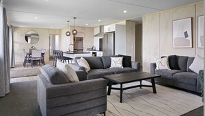 Een moderne woonkamer met grijze banken, een salontafel en een eetgedeelte met een tafel en stoelen.