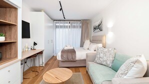 A modern hotel room with a bed, a sofa, a desk, and a small dining table. - Luxurious Sea Point Studio Apartment (Cape Town)