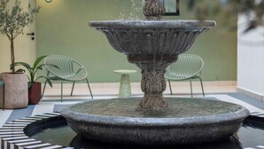 A multi-tiered stone fountain in a courtyard with chairs and potted plants around it. - Luxurious Sea Point Studio Apartment (Cape Town)