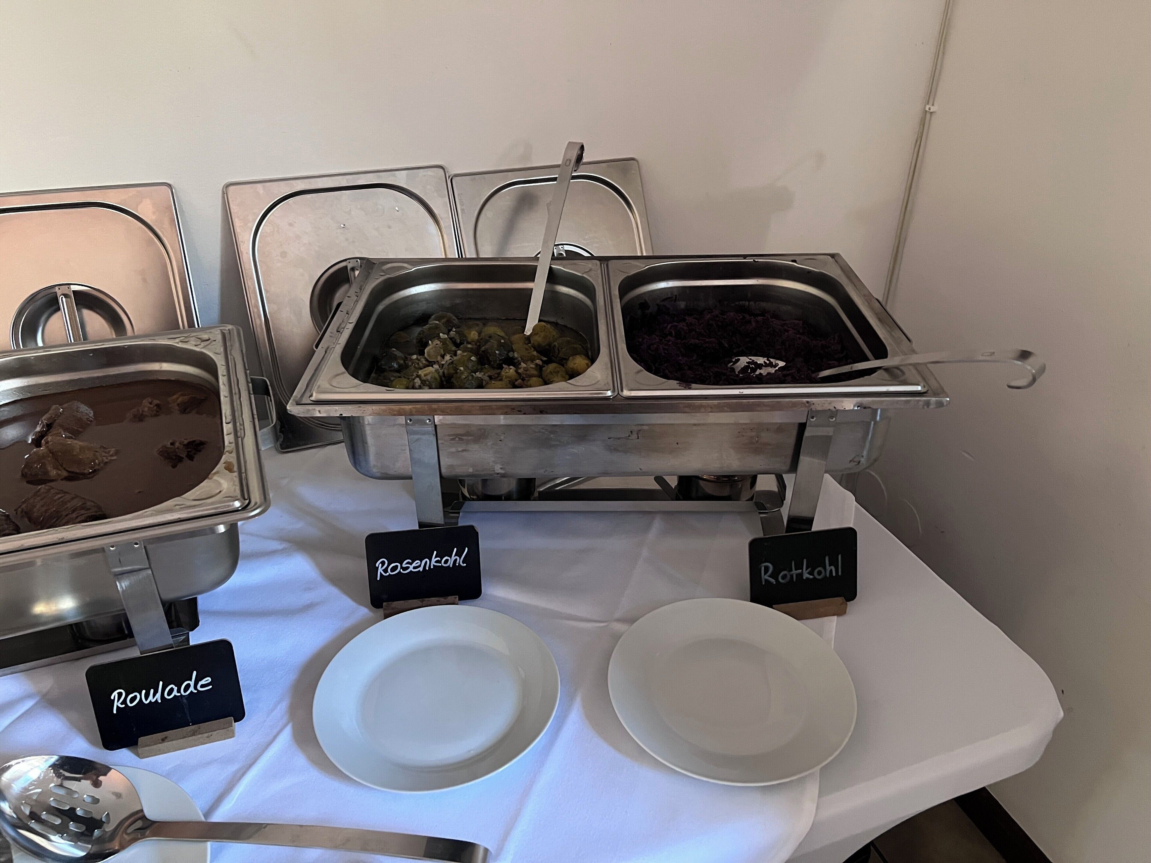 Un bufé con platos identificados, incluyendo Rosenkohl, Roulade y Potkohl.