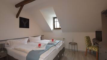 A bedroom with two beds, a small table, a chair, a TV, and a window.