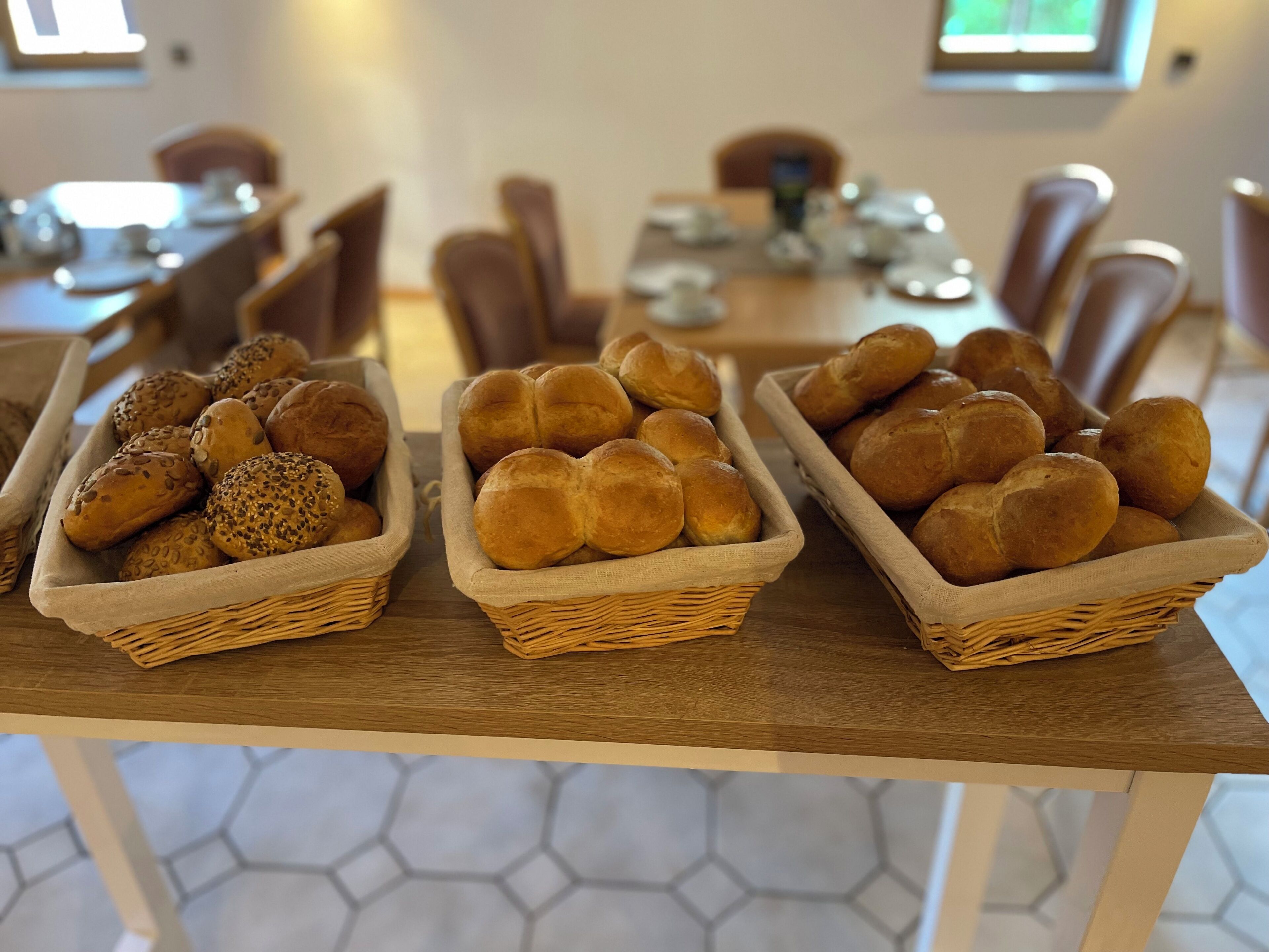 Trois paniers en osier remplis de pain sont posés sur une table en bois dans un coin repas.
