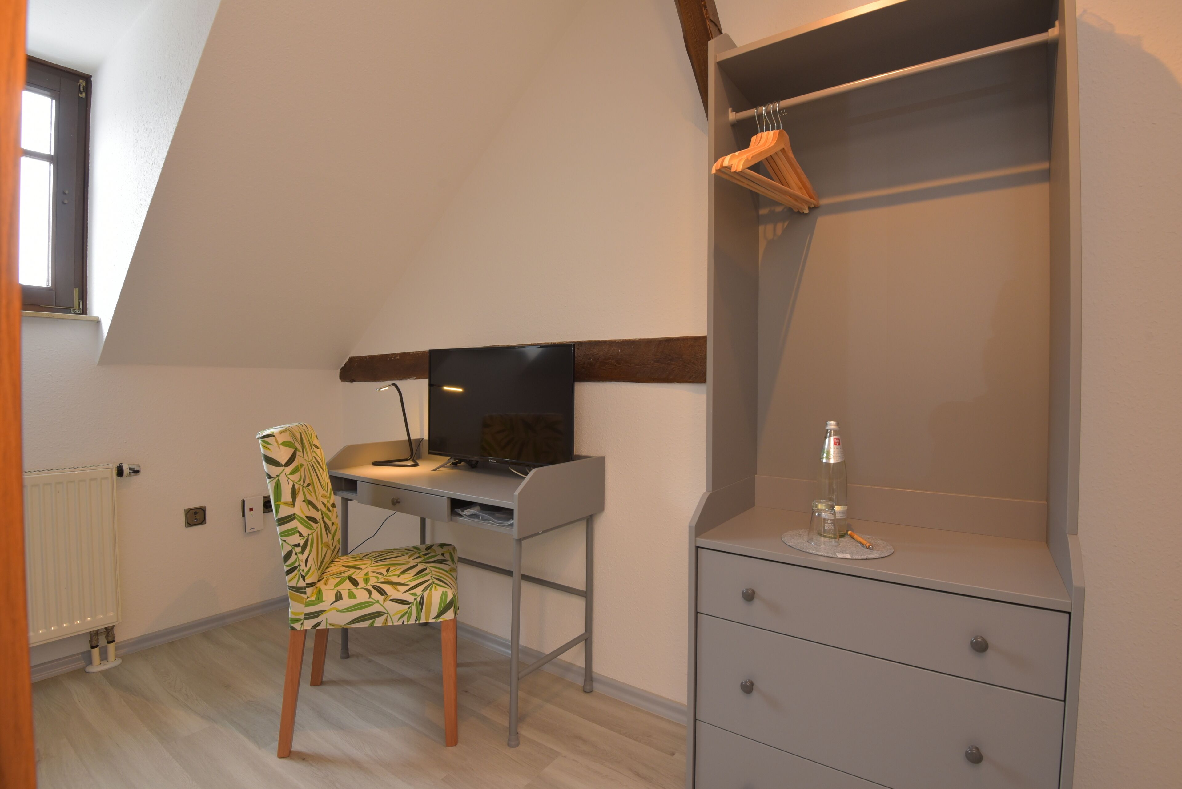 A room with a desk, chair, and a wardrobe.