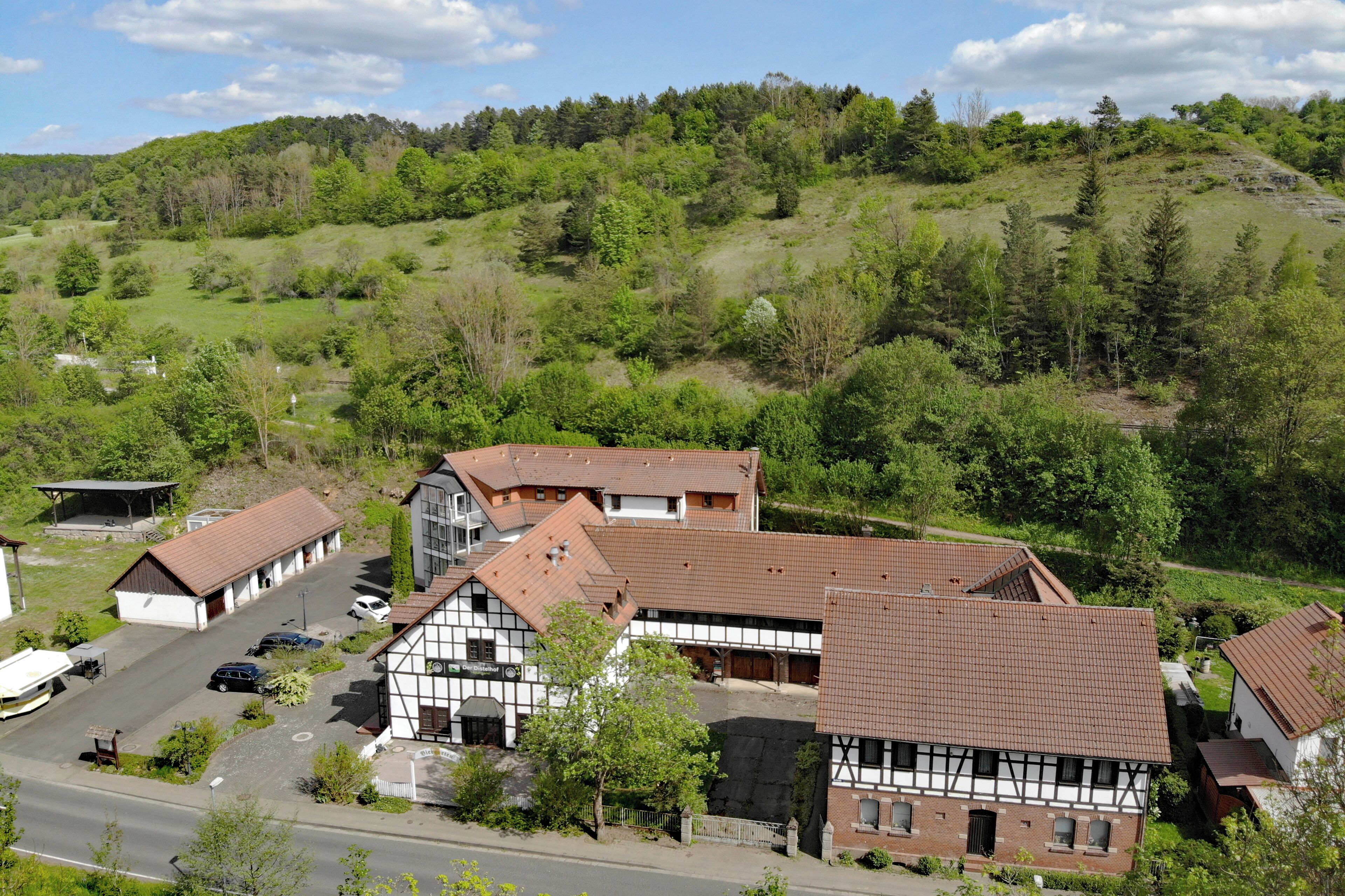 A traditional half-timbered building with a parking area and a road in front.