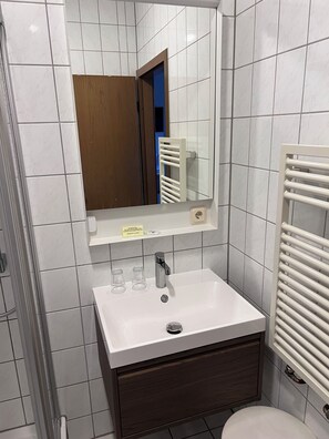 Een badkamer met een witte wastafel, een spiegel en een handdoekrek.