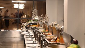 A buffet setup with multiple serving stations, a long table, and overhead lighting. - Violet Hotel (Yanbu)