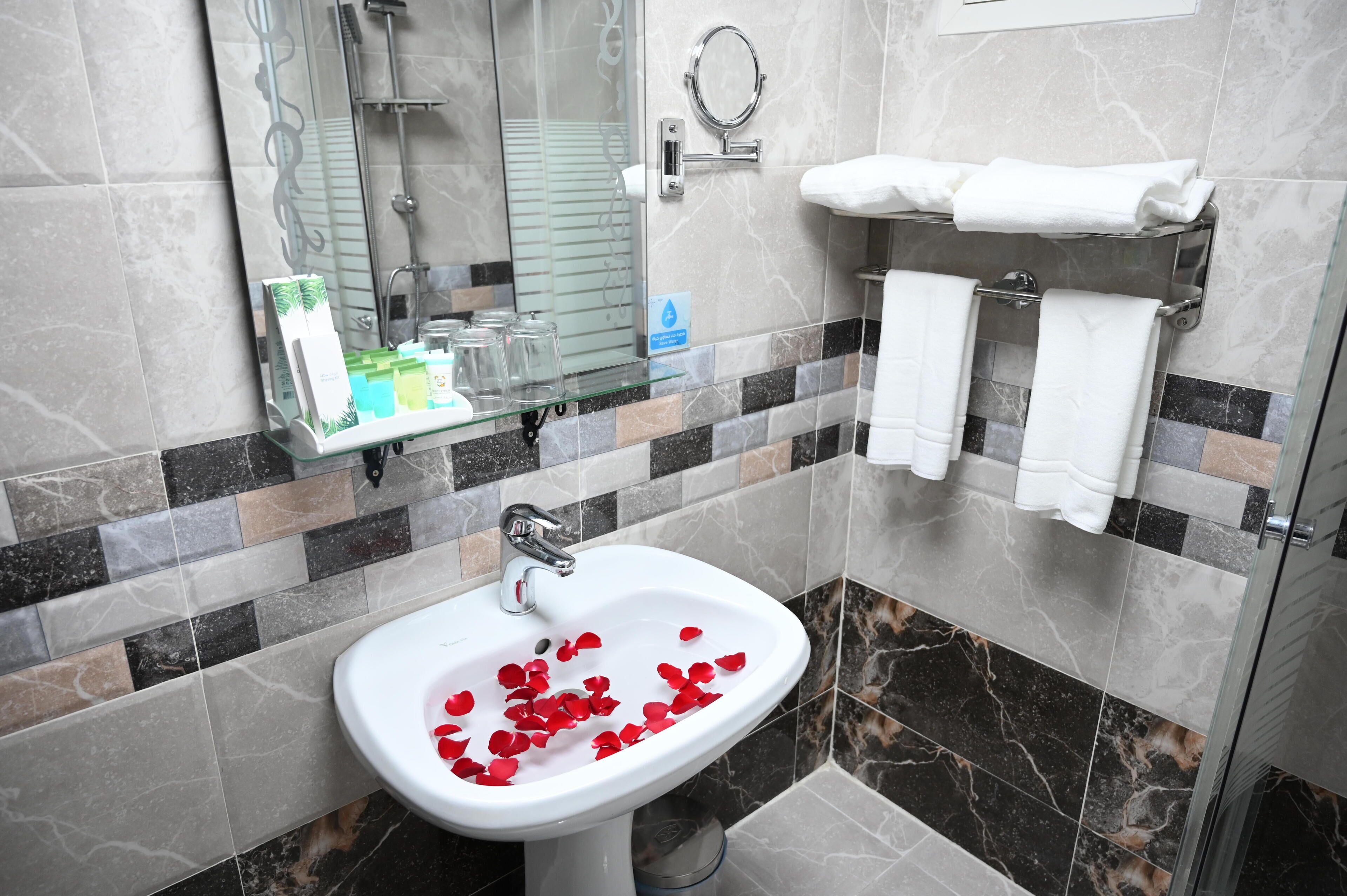 Un baño con lavamanos, cabina de ducha de vidrio y perchero para toallas.
