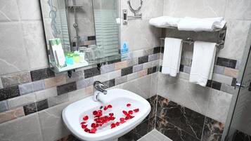 Un baño con lavamanos, cabina de ducha de vidrio y perchero para toallas.