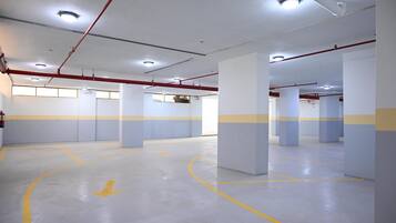 Amplio estacionamiento interior con indicaciones claras y múltiples columnas.