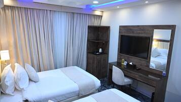Habitación de hotel con dos camas, un escritorio, una silla, un televisor y un armario.
