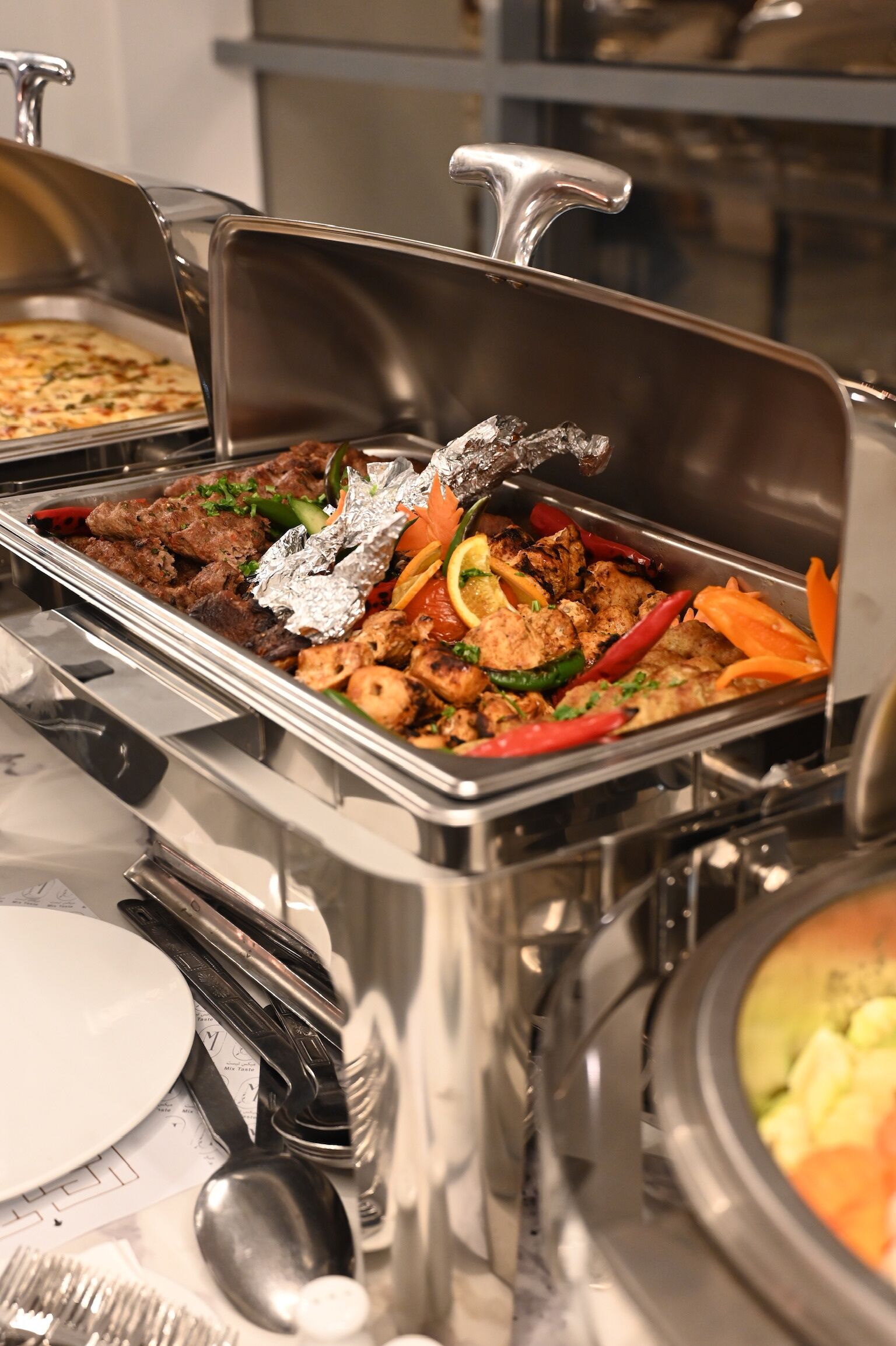 Een buffet met diverse gerechten, waaronder vlees, groenten en verschillende bijgerechten.