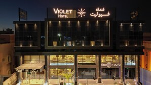 The Violet Hotel with a modern facade, large windows, and a sign in multiple languages. - Violet Hotel (Yanbu)