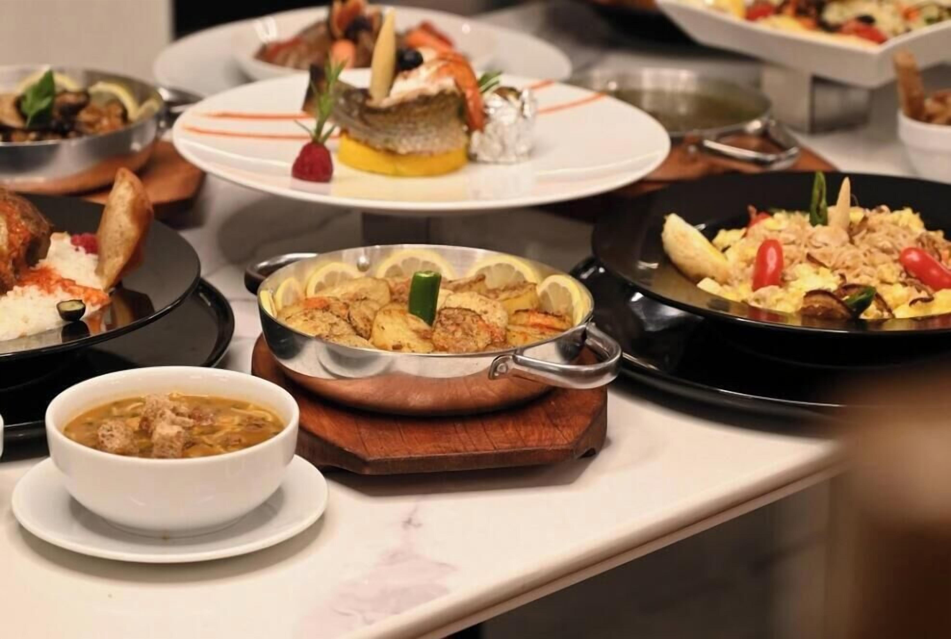 Un bufé con diversos platos, incluyendo mariscos, verduras y arroz.
