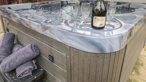 A hot tub with a bottle of Prosecco and glasses. - Greenhaven (Narberth)