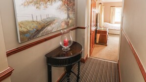 A hallway with a painting, a vase with a candle, and a bed in the background. - Greenhaven (Narberth)