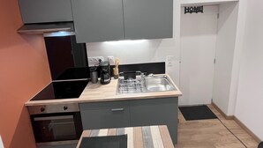 A compact kitchen with grey cabinets, a stainless steel sink, and a black countertop. - Fully-equipped studio just a stone's throw from the Château de Lunéville (Lunéville)