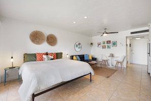 A bedroom with a bed, a nightstand, a sofa, a dining area with chairs, and a ceiling fan. - Historic Shadow Mountain Resort Stay — Pools, Tennis, Near El Paseo & Celeb Hotspots! (Palm Desert)