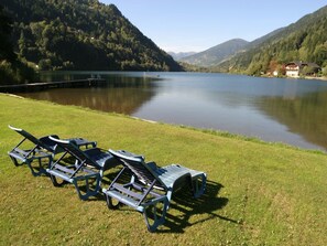A lakeside view with lounge chairs on a grassy area. - Nice apartment in Bad Kleinkirchheim (Bad Kleinkirchheim)