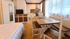 A compact room with a bed, a wooden dining table, and a kitchenette in the background. - Nice apartment in Bad Kleinkirchheim (Bad Kleinkirchheim)