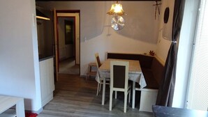 Una habitación con una mesa de comedor, sillas, un banco, una lámpara colgante y vistas a un pasillo.