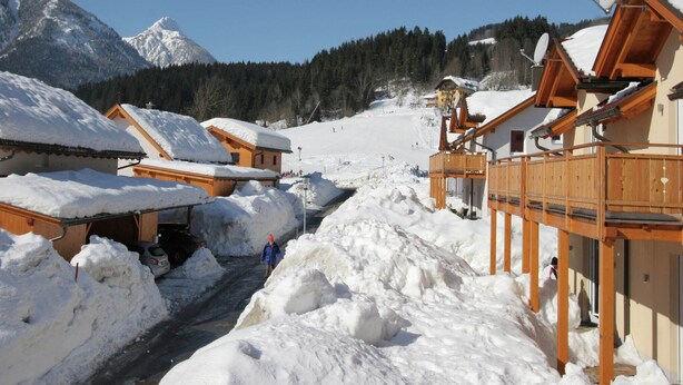 A snow-covered mountain village with wooden chalets, a ski slope in the background, and a clear sky. - Chalet in Koetschach-Mauthen near ski slope (Kötschach-Mauthen)