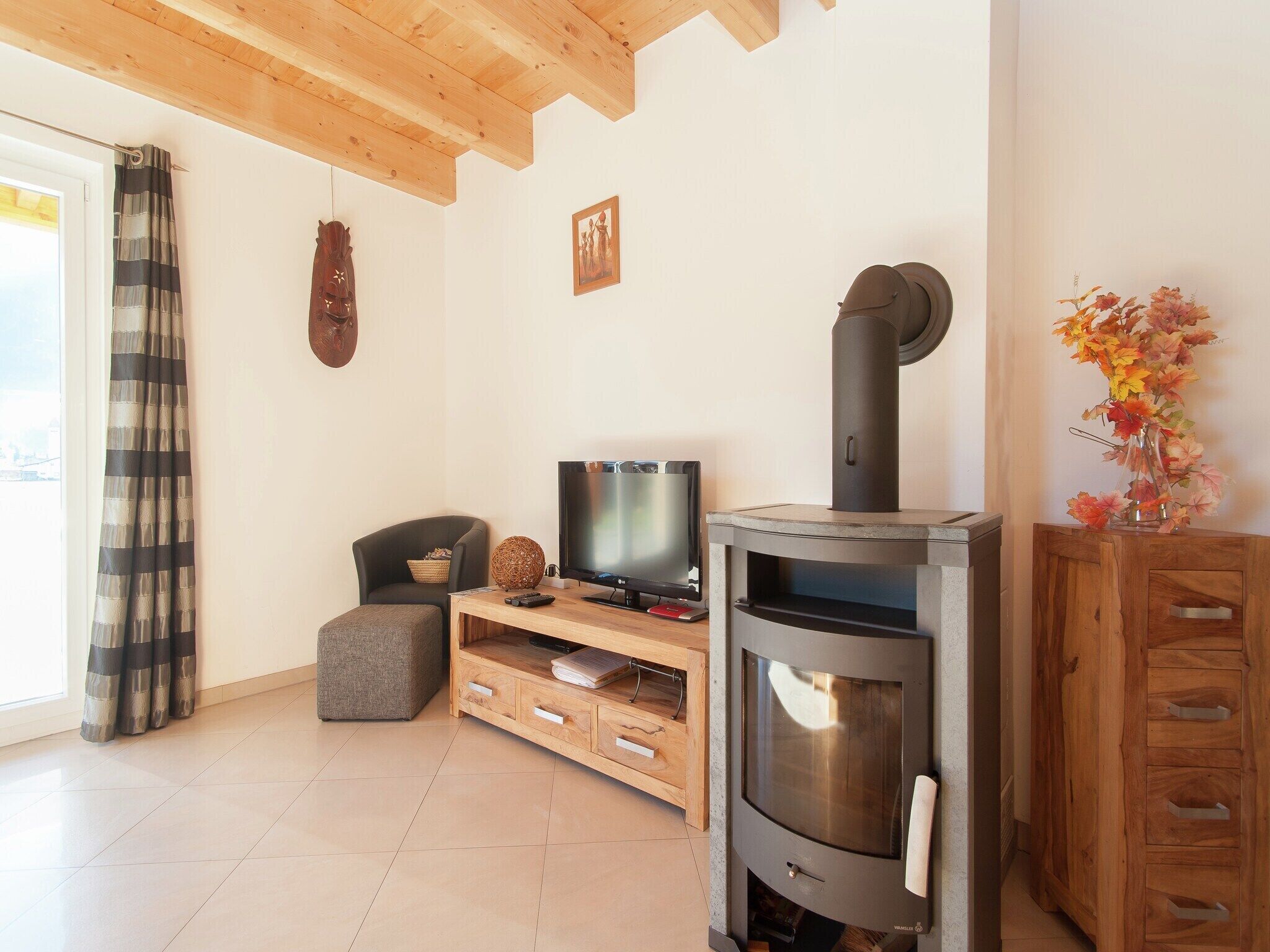 A living room with a TV, wooden furniture, a fireplace, and a window with curtains.