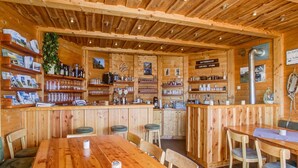 A wooden interior with a bar area, seating, and shelves with various items.
