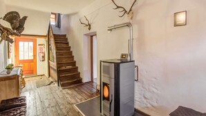 A cozy living room with a wood-burning stove, a staircase, and a rustic decor including antlers on the wall.