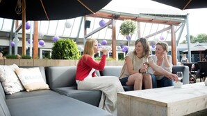 Een terras met een grijze bank en een houten tafel.