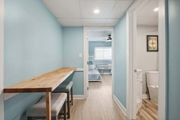 Een gang die uitkomt in een slaapkamer met een bed, een plafondventilator en een bord met daarop 'Beach Patrol'.