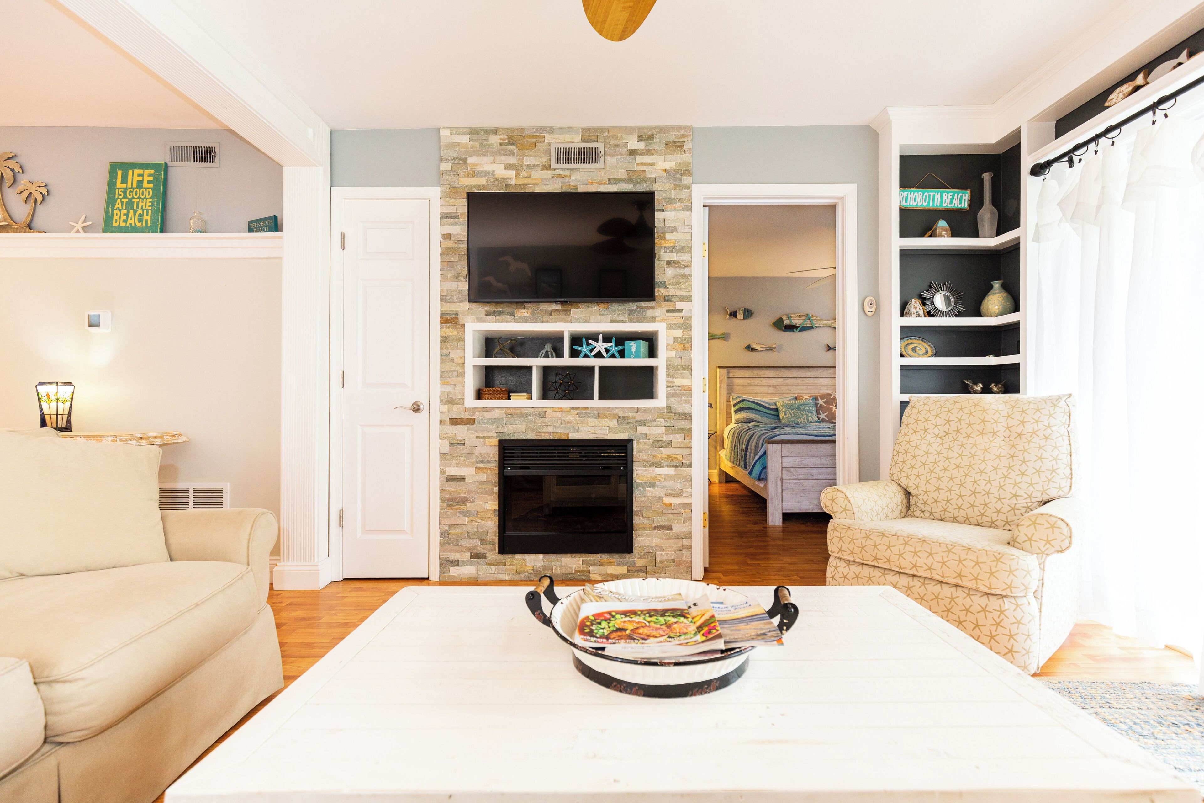 Una sala de estar con chimenea, una mesa de comedor con un asado, un sofá y un sillón estampado.