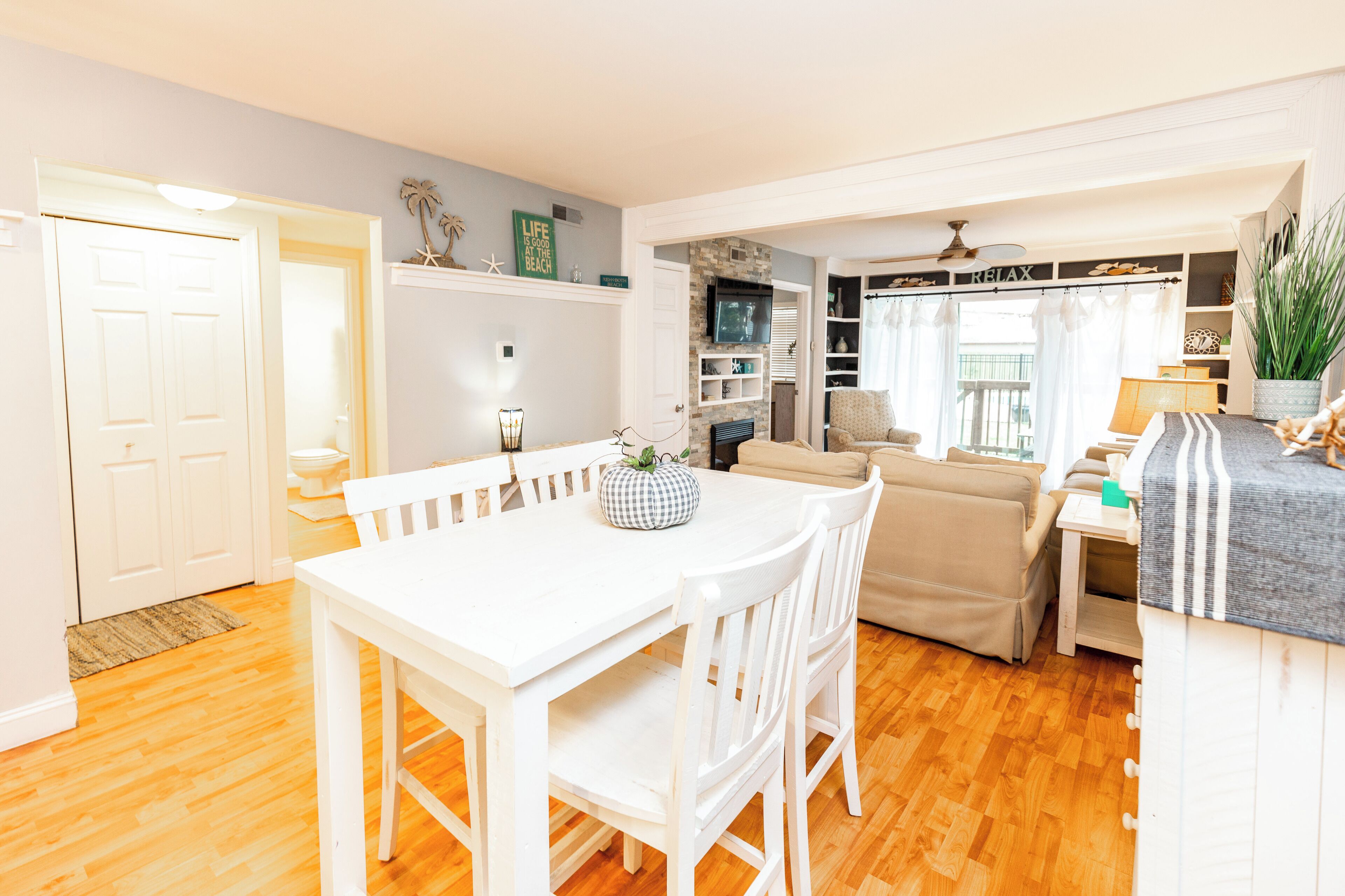 A spacious living area with a dining table and chairs, a sofa, a TV, and a balcony with a view.