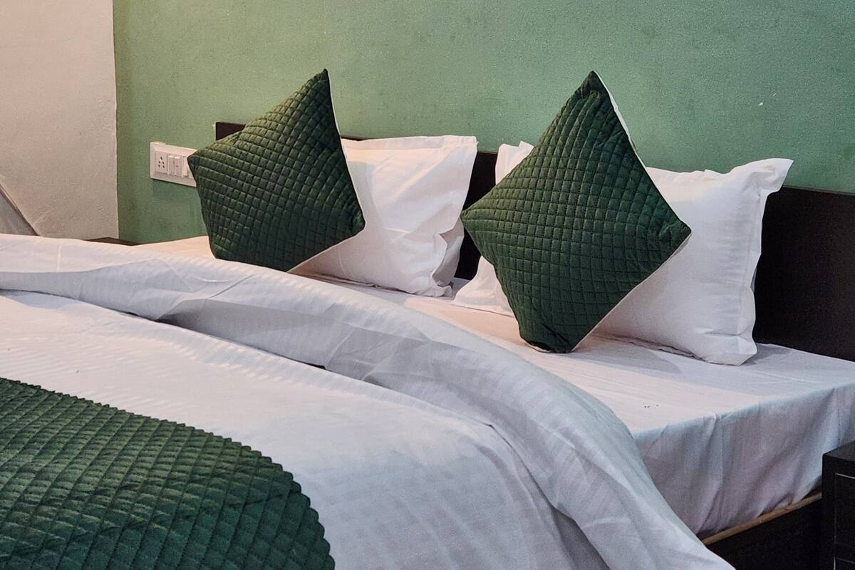 A hotel room with two beds, each with green and white bedding.