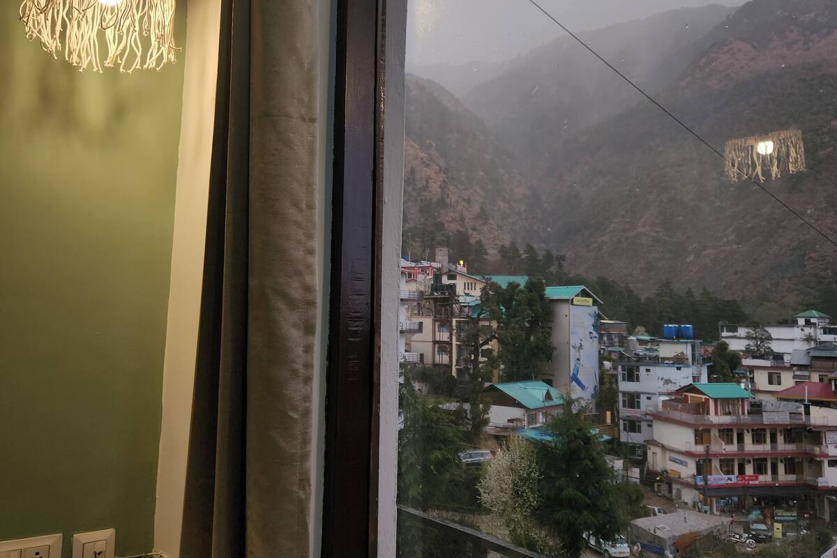 A view from a window overlooking a town with buildings and mountains in the background.