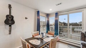 Un comedor con mesa, sillas y una guitarra colgada en la pared.