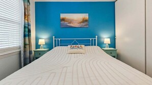 Un dormitorio con una cama, un cuadro en la pared y dos mesitas de noche con lámparas.