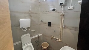 Een badkamer met toilet, bidet en douchecabine.