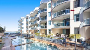 A modern hotel with a pool area, multiple balconies, and outdoor seating.