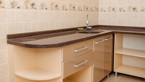A modern kitchen with a built-in microwave, a sink, and a tea set on a shelf. - Armon Apart Hotel (Khujand)