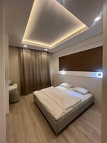 Un dormitorio moderno con cama, mesita de noche y un amplio ventanal con cortinas.